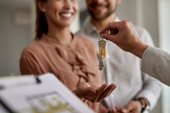 Real estate transactions concept. Close-up of real estate agent giving new house keys to a couple.