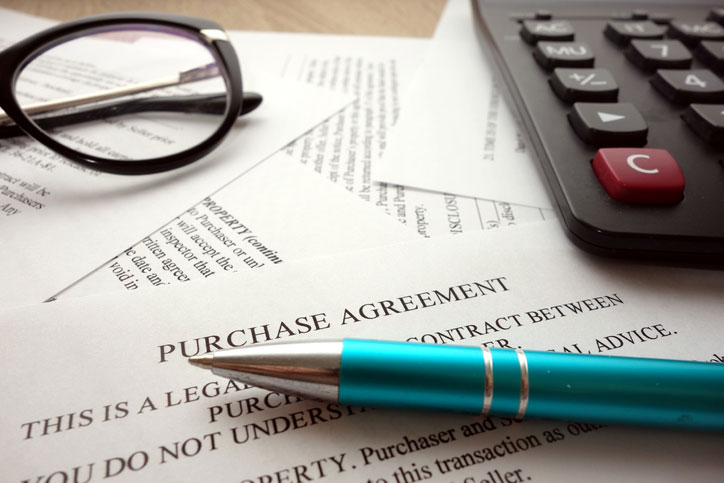 Purchase agreement document for filling and signing on desk.