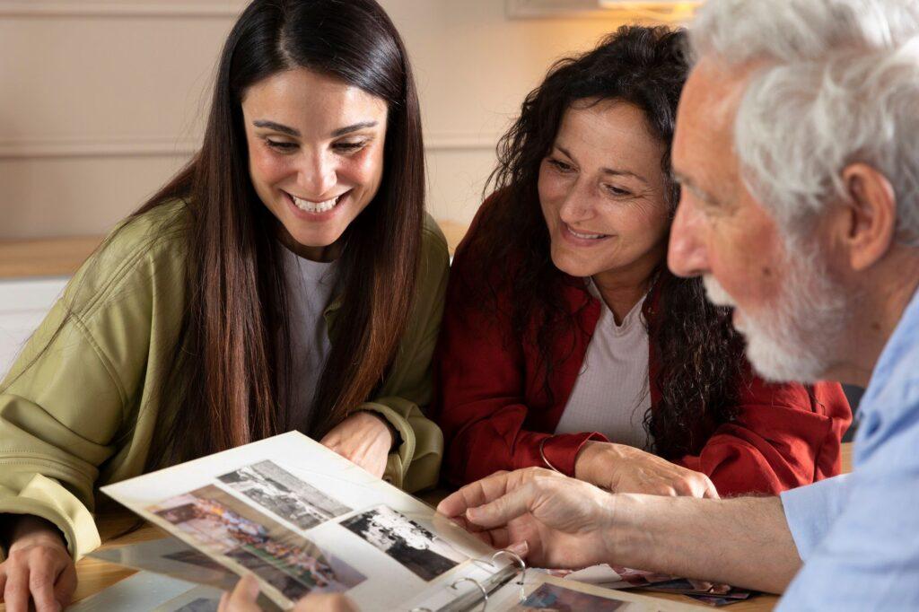 Two women, an executor and trustee, sitting with an older man smiling while looking through a photo album